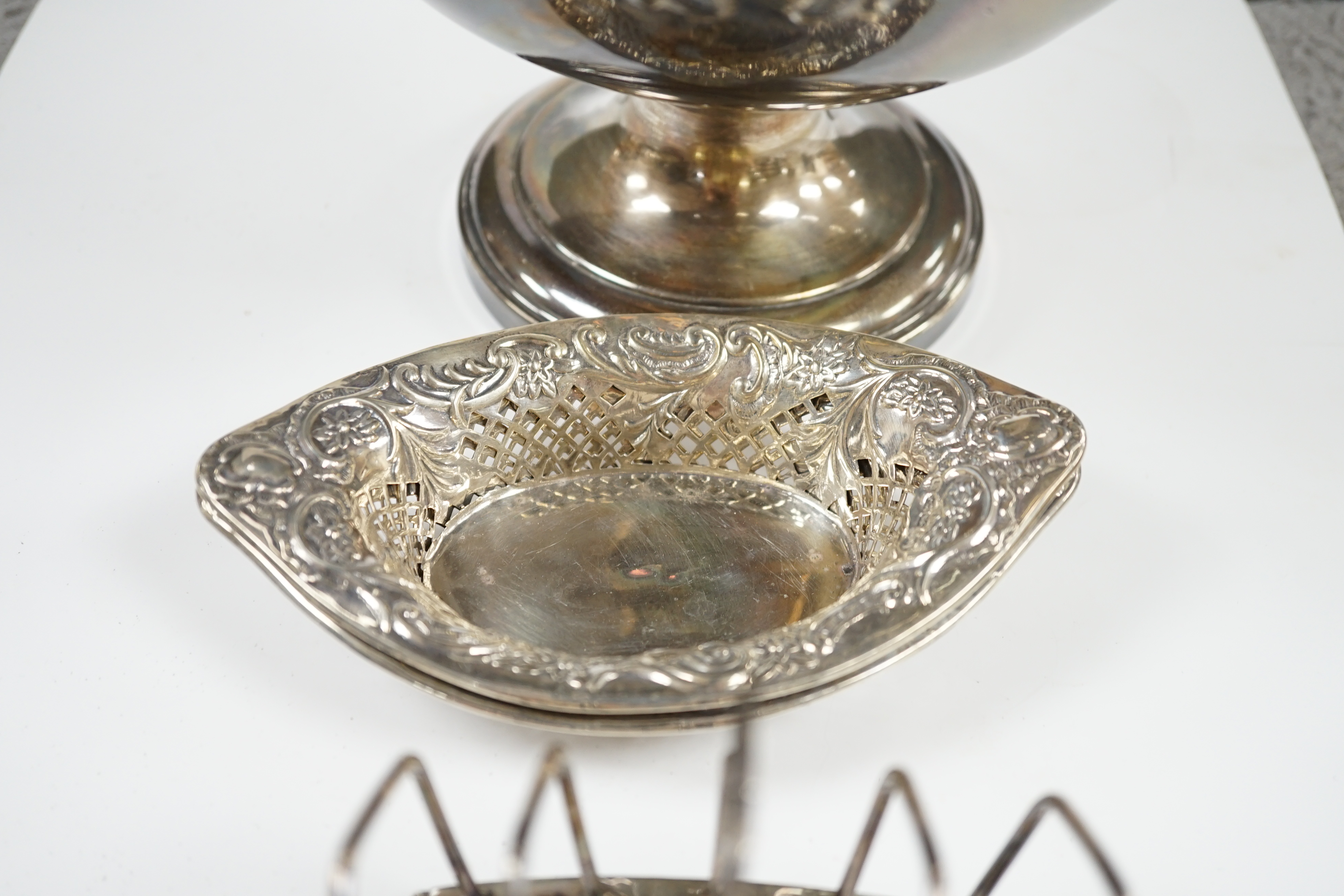 A pair of late Victorian pierced silver navette shaped bonbon dishes, 15.4cm, a silver five bar toast rack and a plated punch bowl and cover. Condition - poor to fair